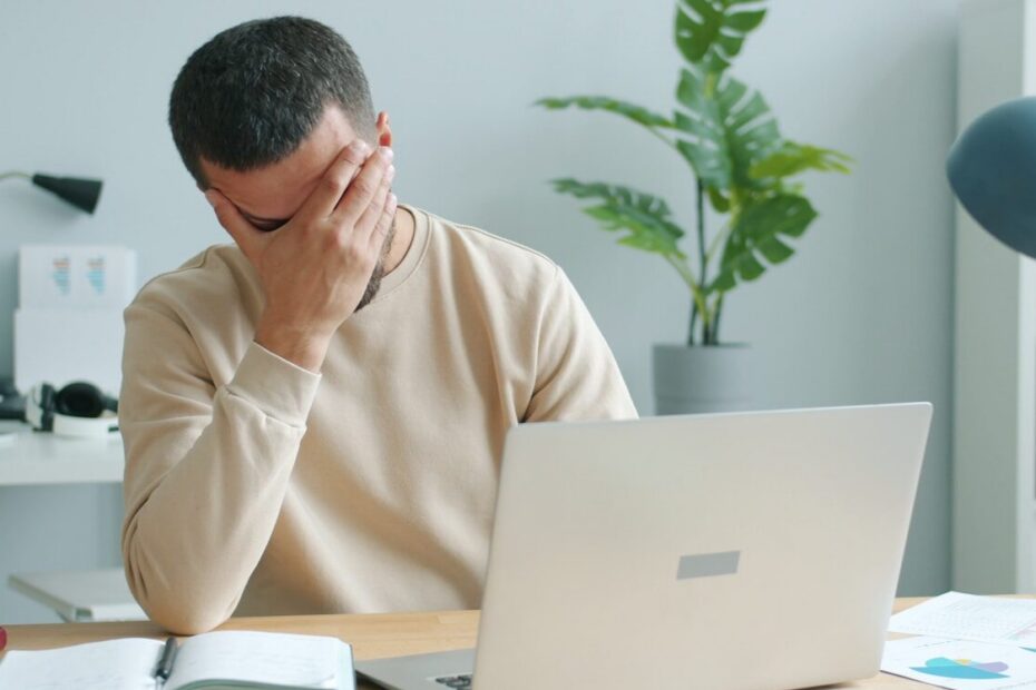 Man rubbing his face in front of laptop.